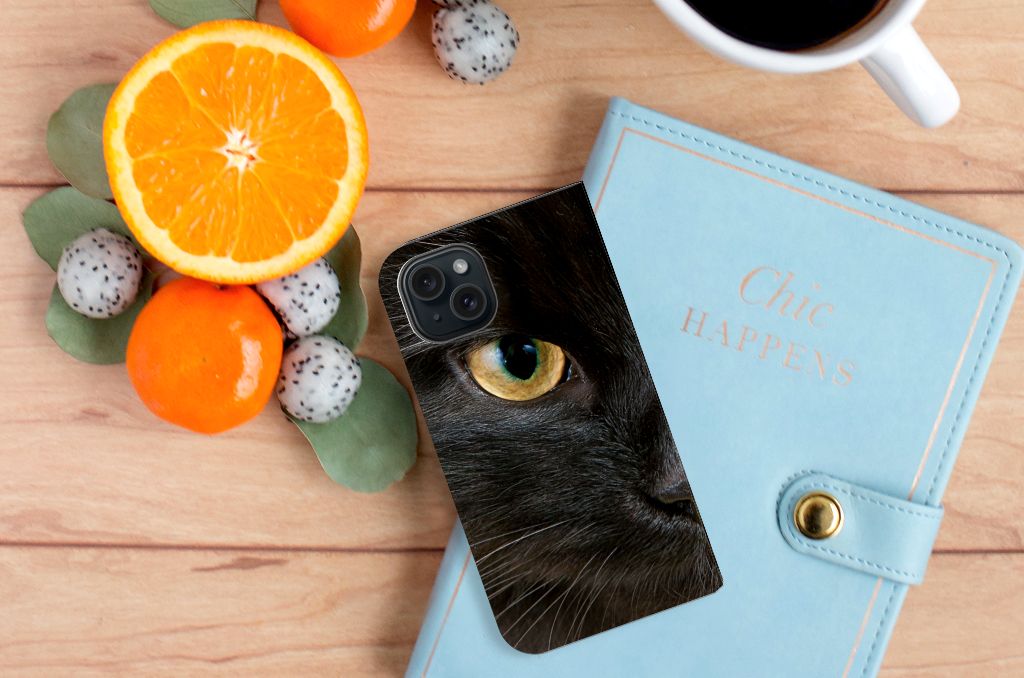 iPhone 15 Hoesje maken Zwarte Kat met een close-up van de oog van een zwarte kat, omringd door citrusvruchten.