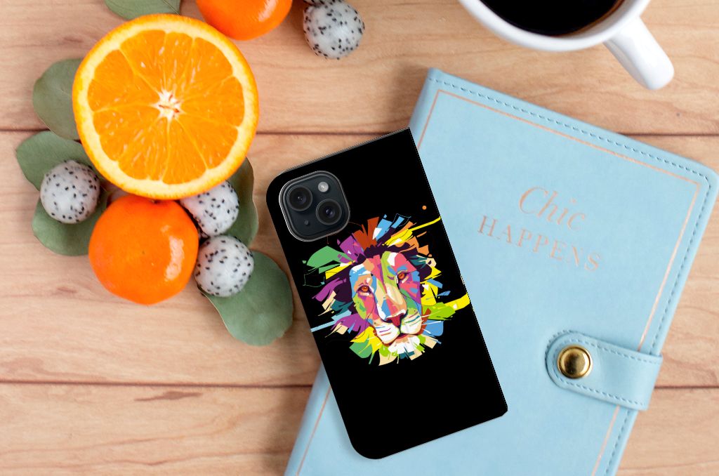 iPhone 15 Magnet Case Lion Color met kleurrijk leeuwontwerp op telefoonhoesje, omringd door fruit en notitieboek.