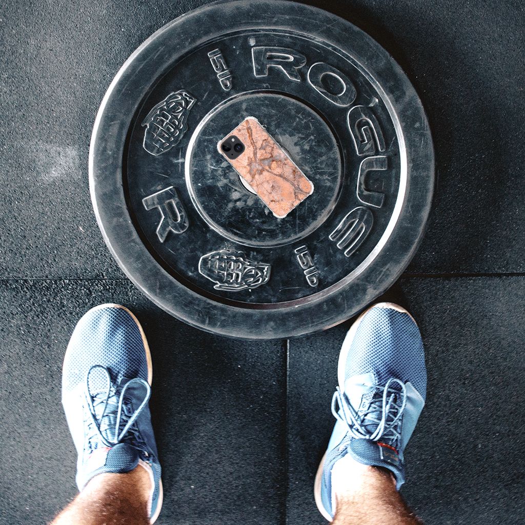 iPhone 15 Plus Anti-Shock Hoesje Marmer Oranje smartphone op gewicht schijf met sneakers