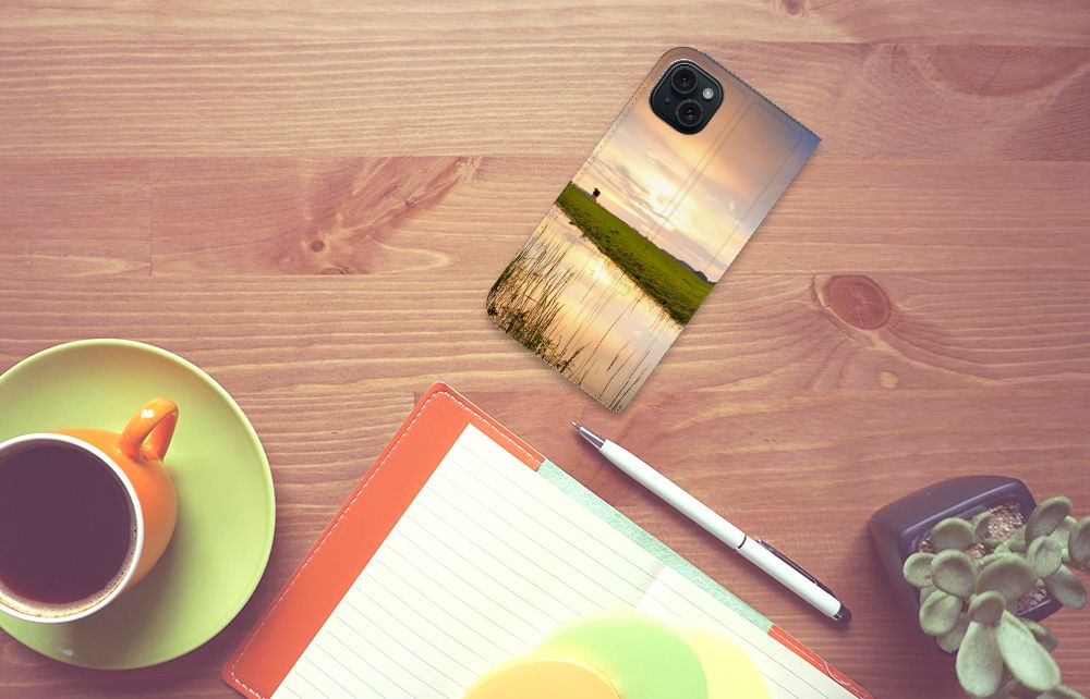 iPhone 15 Plus Hoesje maken Koe op een bureau met een ondergang, een koffie en een notitieboekje.