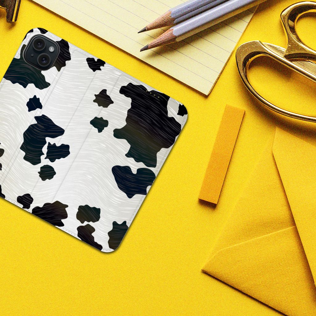 iPhone 15 Plus Hoesje maken Koeienvlekken met zwart-witte vlekken op een geel bureau met kantoorbenodigdheden.