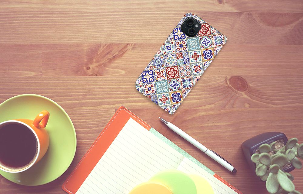 iPhone 15 Plus Standcase Tiles Color met kleurrijk tegelpatroon op houten tafel met koffie ☕.