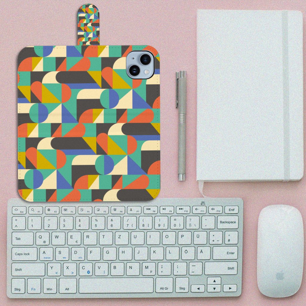 iPhone 15 Plus Telefoon Hoesje Funky Retro met kleurrijk geometrisch patroon op een bureau met toetsenbord en notitieboekje.