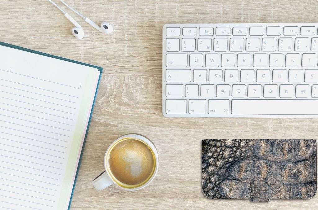 iPhone 15 Plus Telefoonhoesje met Pasjes Krokodillenprint, een stijlvolle toevoeging aan je bureau, met koffie en notitieboekje.