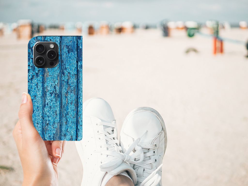 iPhone 15 Pro Book Wallet Case Wood Blue met blauw houten design, vastgehouden op het strand 🏖️.