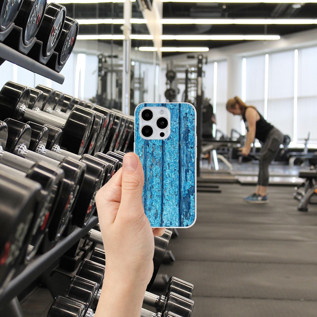 iPhone 15 Pro Bumper Hoesje Wood Blue in hand met gym apparatuur op de achtergrond.