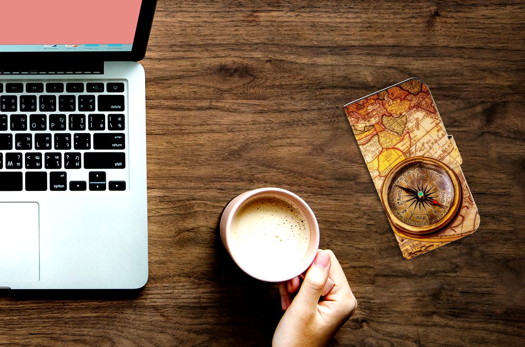 iPhone 15 Pro Flip Cover Kompas naast een laptop en koffie, perfect voor reizigers.