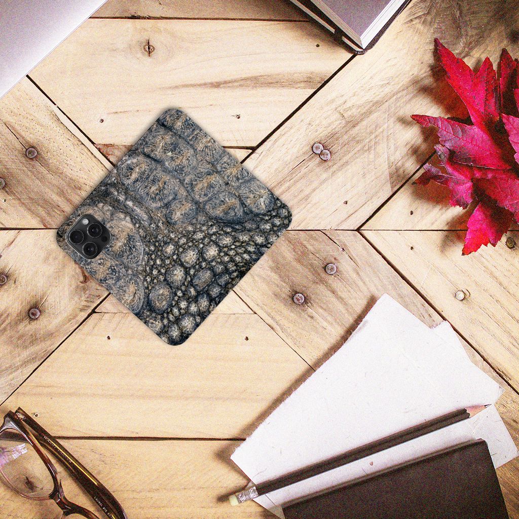 iPhone 15 Pro Max Hoesje maken Krokodillenprint op een houten tafel met boeken en een plantje.