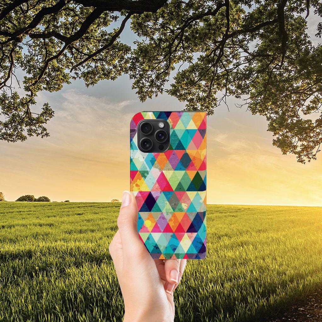 iPhone 15 Pro Max Hoesje met Magneet Geruit in kleurrijk ruitjesdesign, gehouden tegen een zonnige achtergrond.