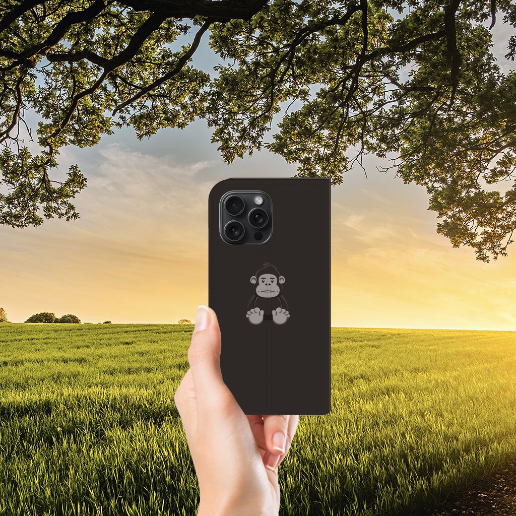 iPhone 15 Pro Max Magnet Case Gorilla met schattig aapje ontwerp in hand tegen een natuurlijke achtergrond.