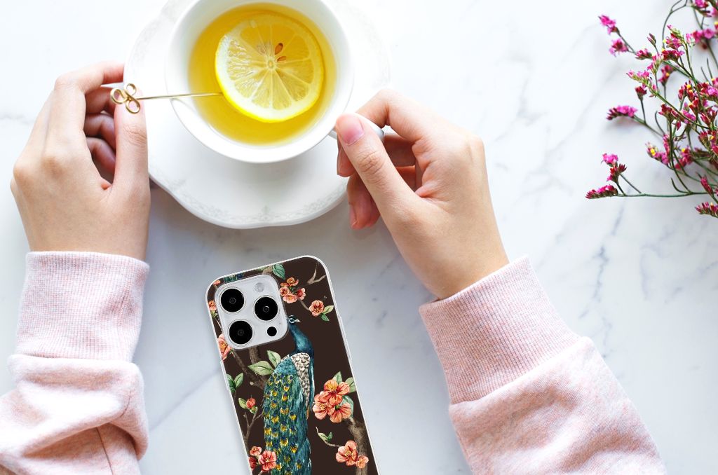 iPhone 15 Pro Max TPU Hoesje Pauw met Bloemen met een hand die een kopje thee vasthoudt.