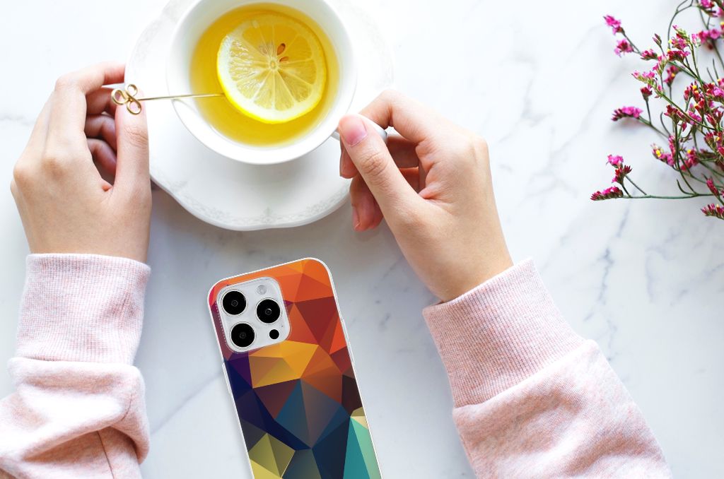 Een vrouw houdt een kopje thee vast met een iPhone 15 Pro Max TPU Hoesje Polygon Color met kleurrijke geometrische patronen.