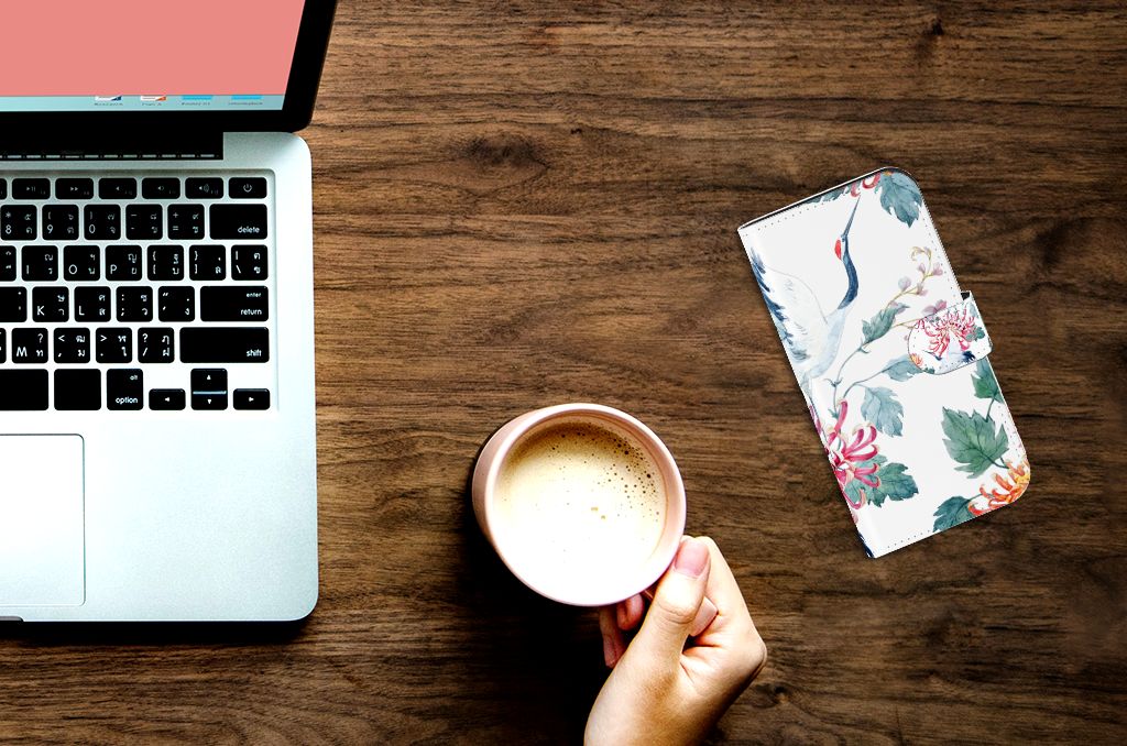 iPhone 15 Pro Telefoonhoesje met Pasjes Bird Flowers naast een laptop en een kopje koffie.