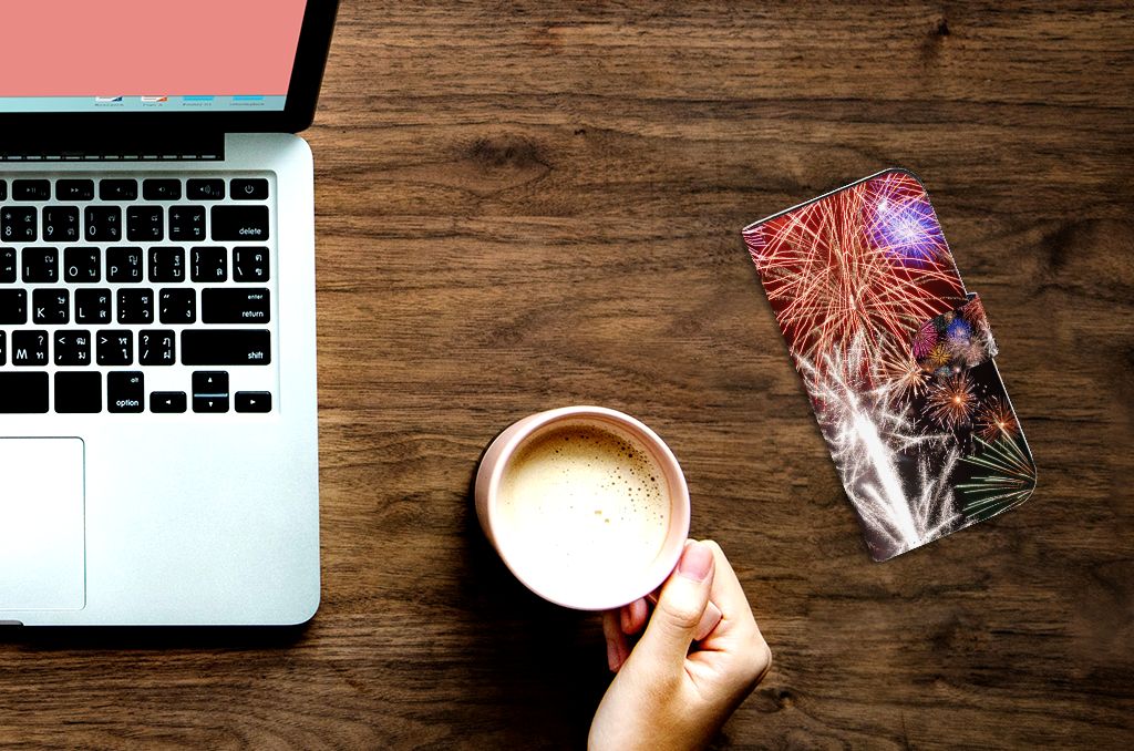 iPhone 15 Pro Wallet Case met Pasjes Vuurwerk ligt op een bureau naast een laptop en een kop koffie.