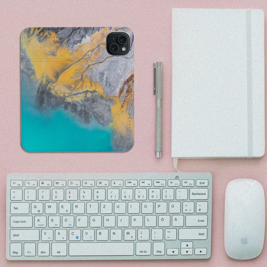 iPhone 15 Standcase Marble Blue Gold met prachtig marmerdesign op bureau naast toetsenbord en notitieboek.
