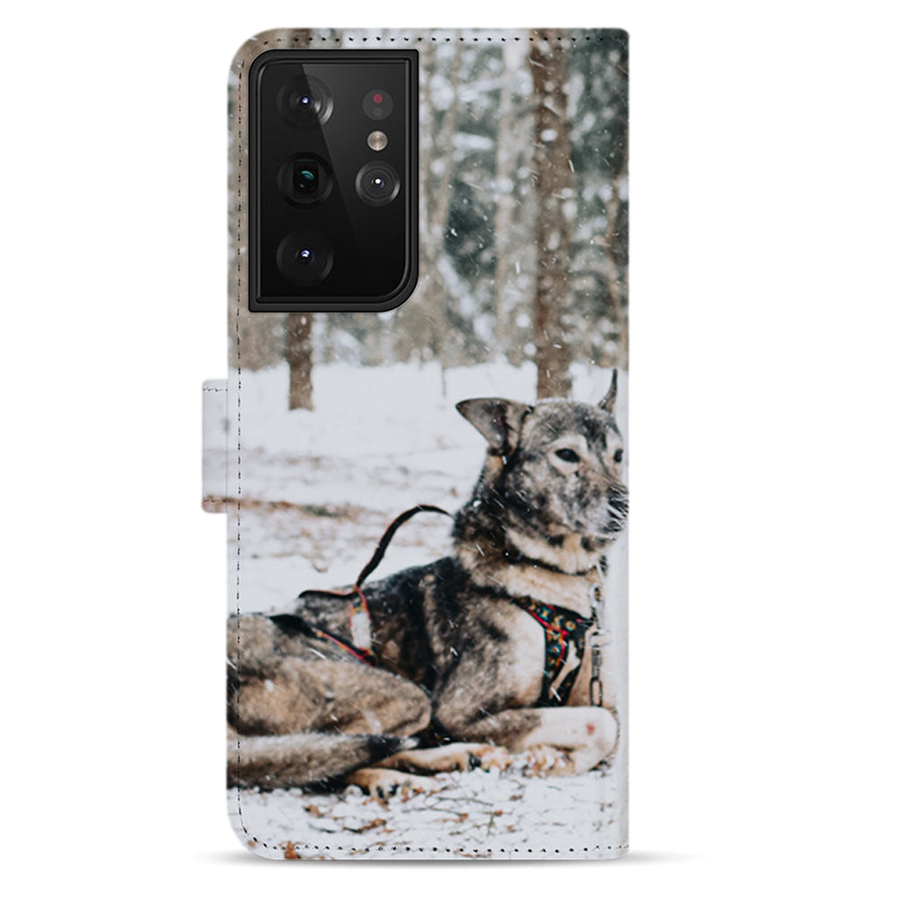 Liggende sledehond in de sneeuw op de achterkant van de Galaxy S21 Ultra bookcase, grote camera-uitsparing linksboven